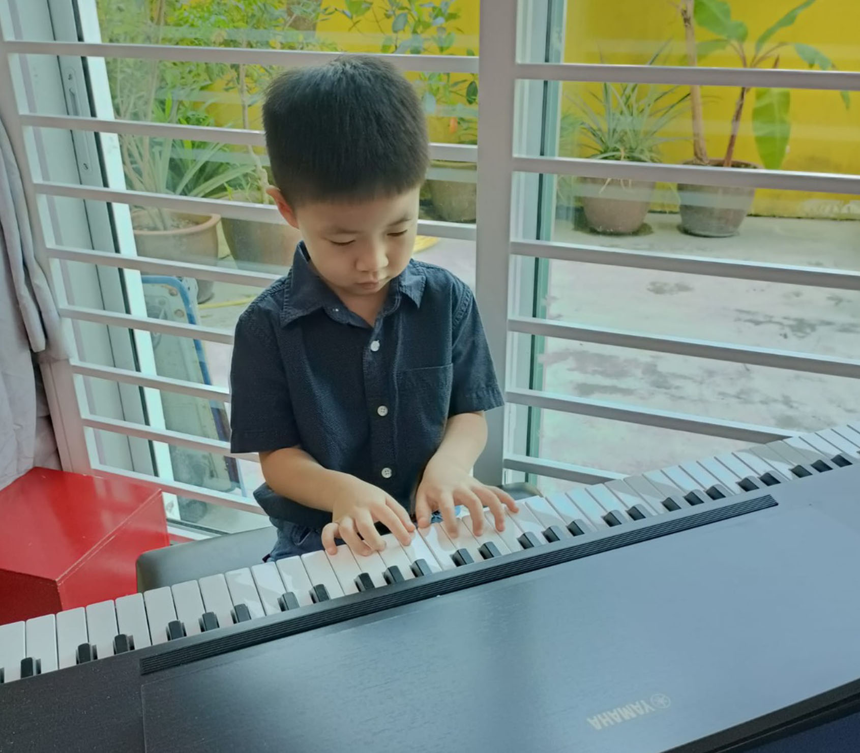 A little boy playing the piano at Eduwis Preschool Malaysia